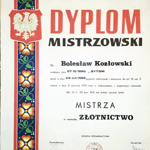Dyplom mistrzowski na tle złotej wstęgi i pieczęci.