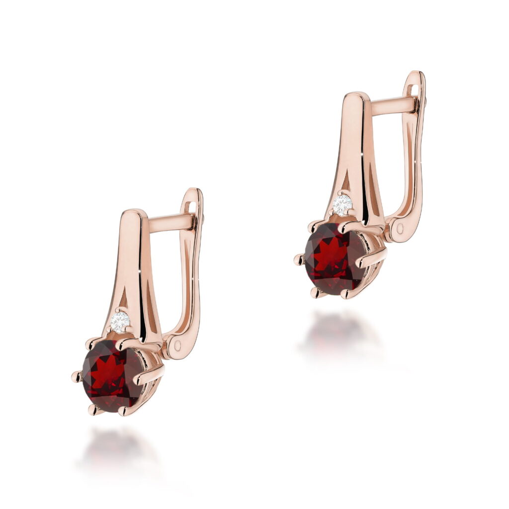 Złote kolczyki z czerwonymi kamieniami i małymi diamentami, eleganckie i stylowe.