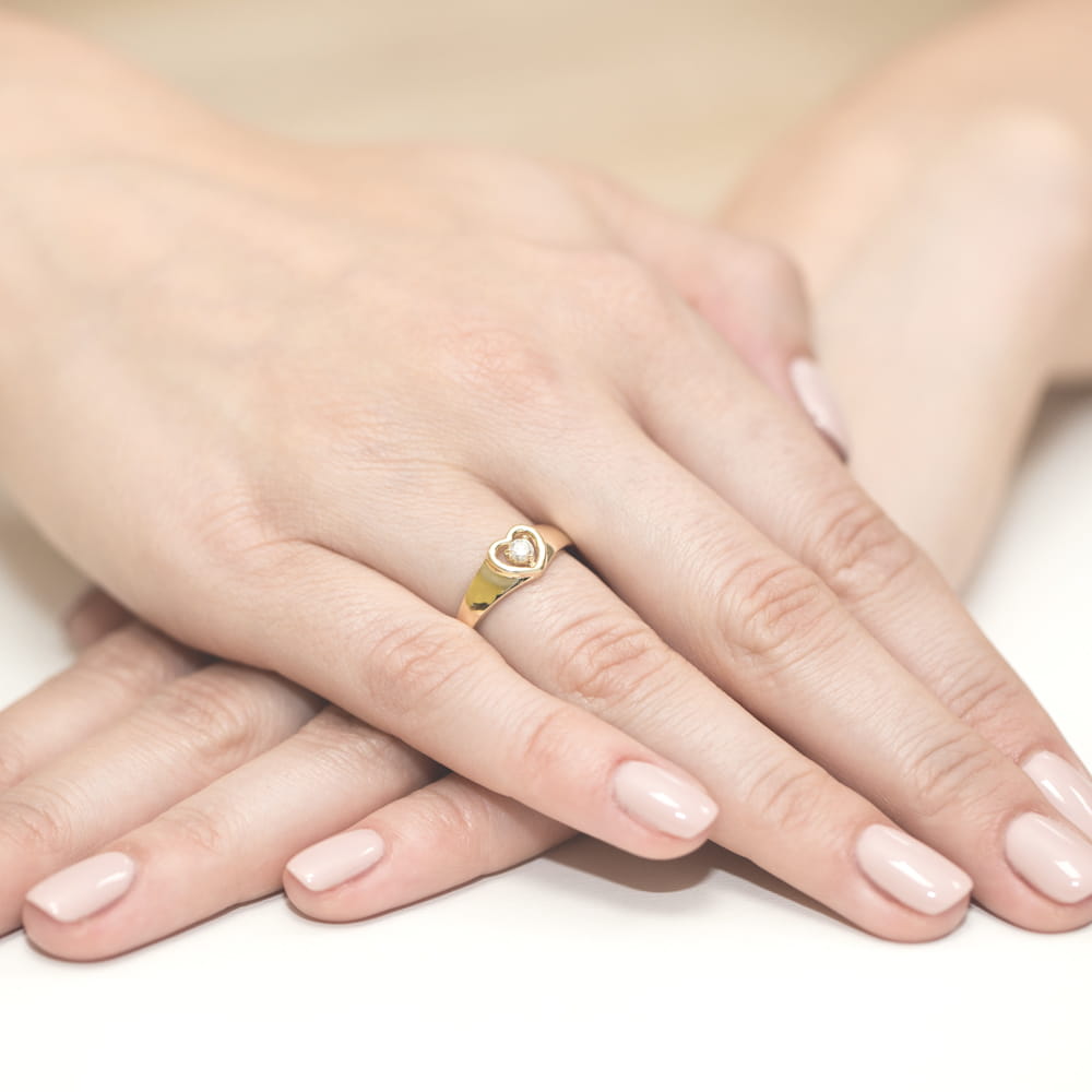 W0001.Z3.DIW.01_4 Złoty pierścionek w kształcie serca na palcu, dłonie z delikatnym manicure w jasnym kolorze.