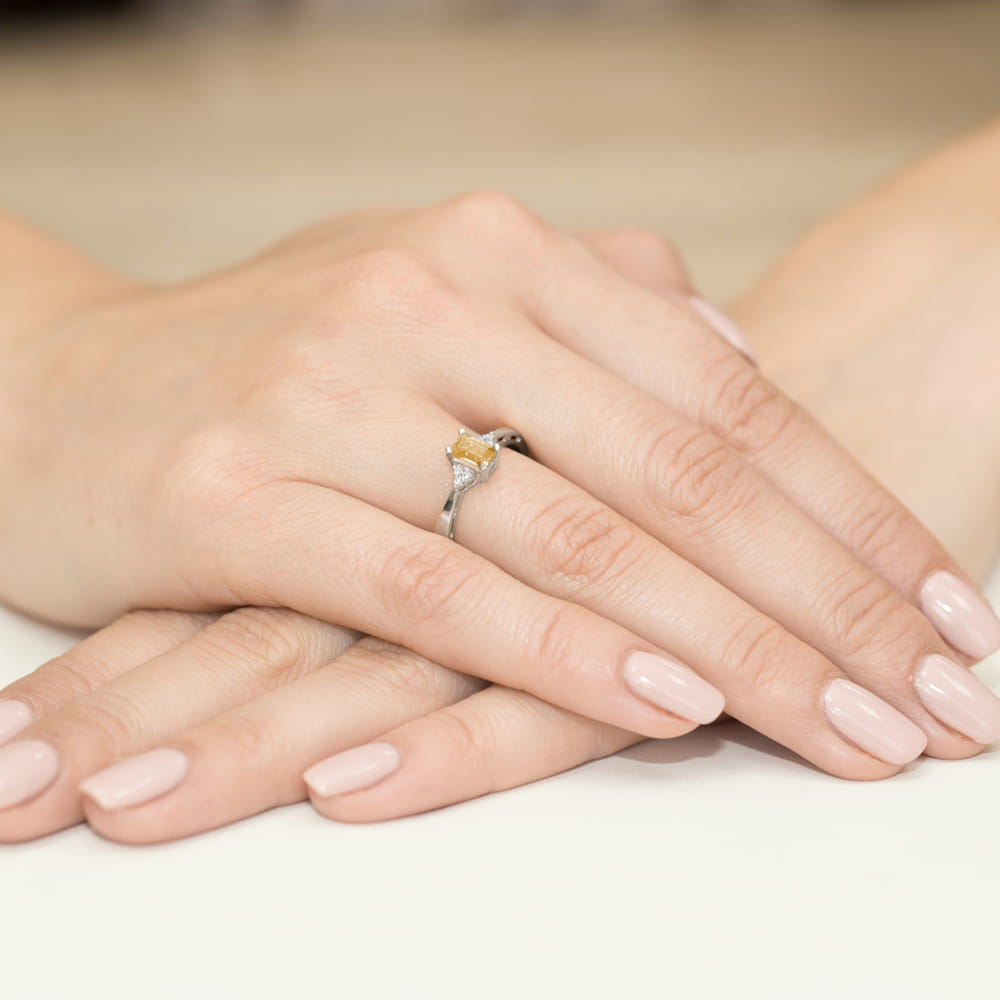 W0002.B3.CIY.01_4 Na dłoniach z delikatnym manicure spoczywa srebrny pierścionek z żółtym kamieniem.