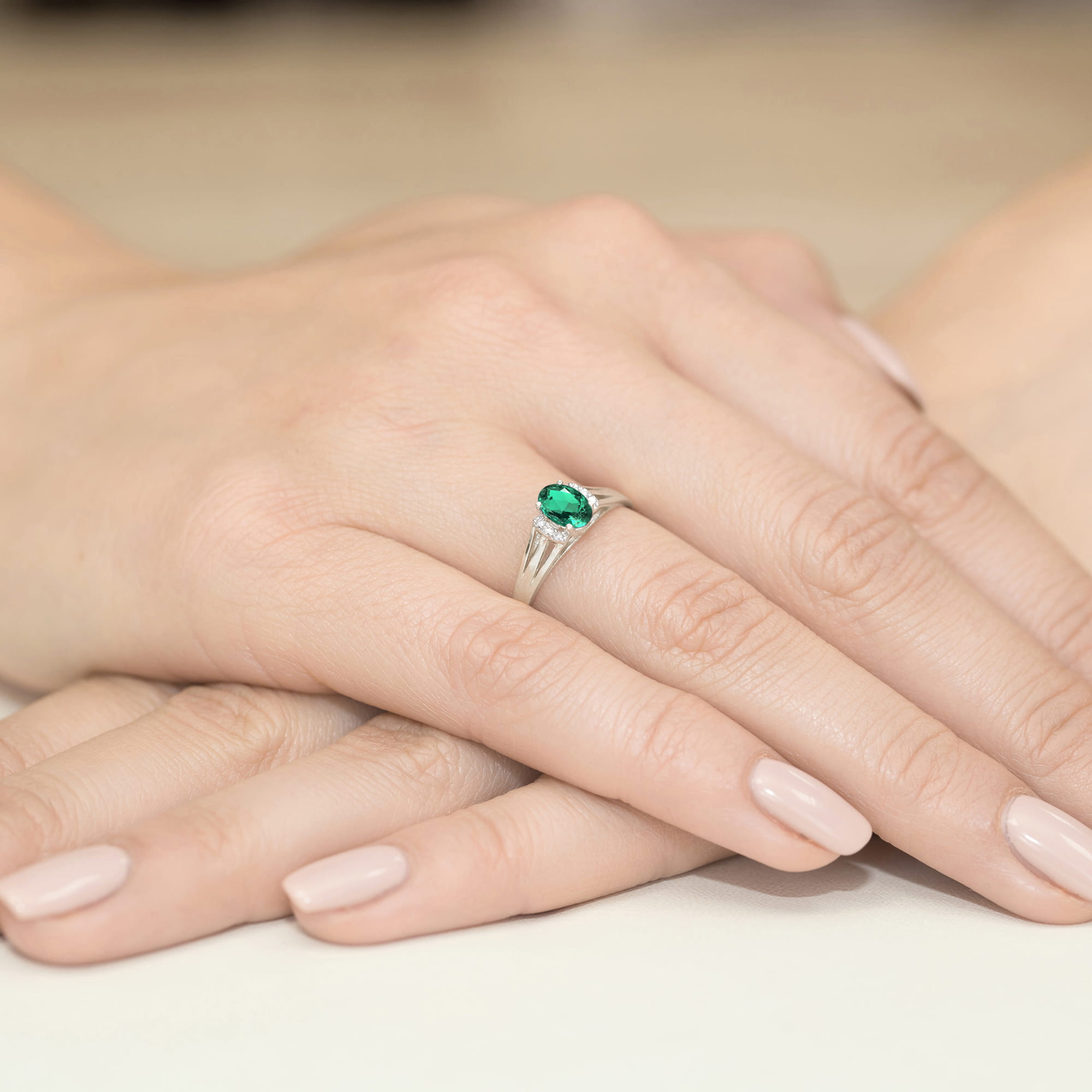 W0005.B3.EMG.01_4 Na dłoni widać srebrny pierścionek z zielonym kamieniem, otoczony delikatnymi, zadbanymi palcami.