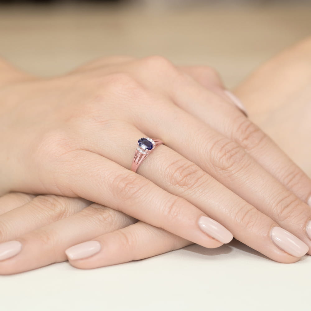 W0005.R3.SAB.01_4 Różowa pierścionek z niebieskim kamieniem na palcu, dłonie z delikatnym manicure w jasnym kolorze.