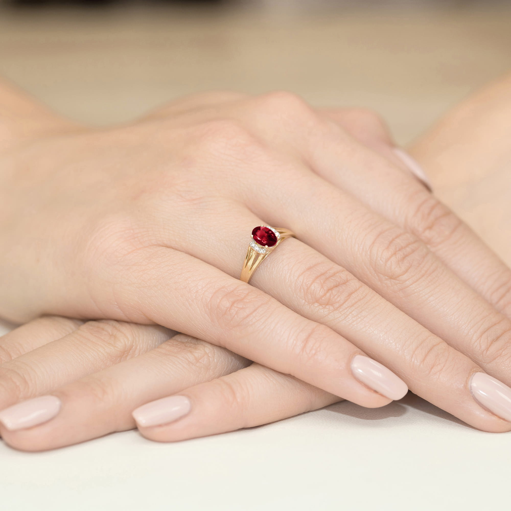 W0005.Z3.GAR.01_4 Złoty pierścionek z czerwonym kamieniem na palcu, dłonie z delikatnym manicure w jasnym kolorze.
