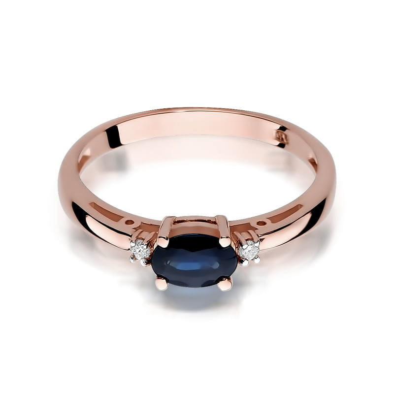 W0006.R3.SAB.01_2 Różowe złote pierścionek z owalnym, granatowym kamieniem i trzema małymi diamentami po bokach.