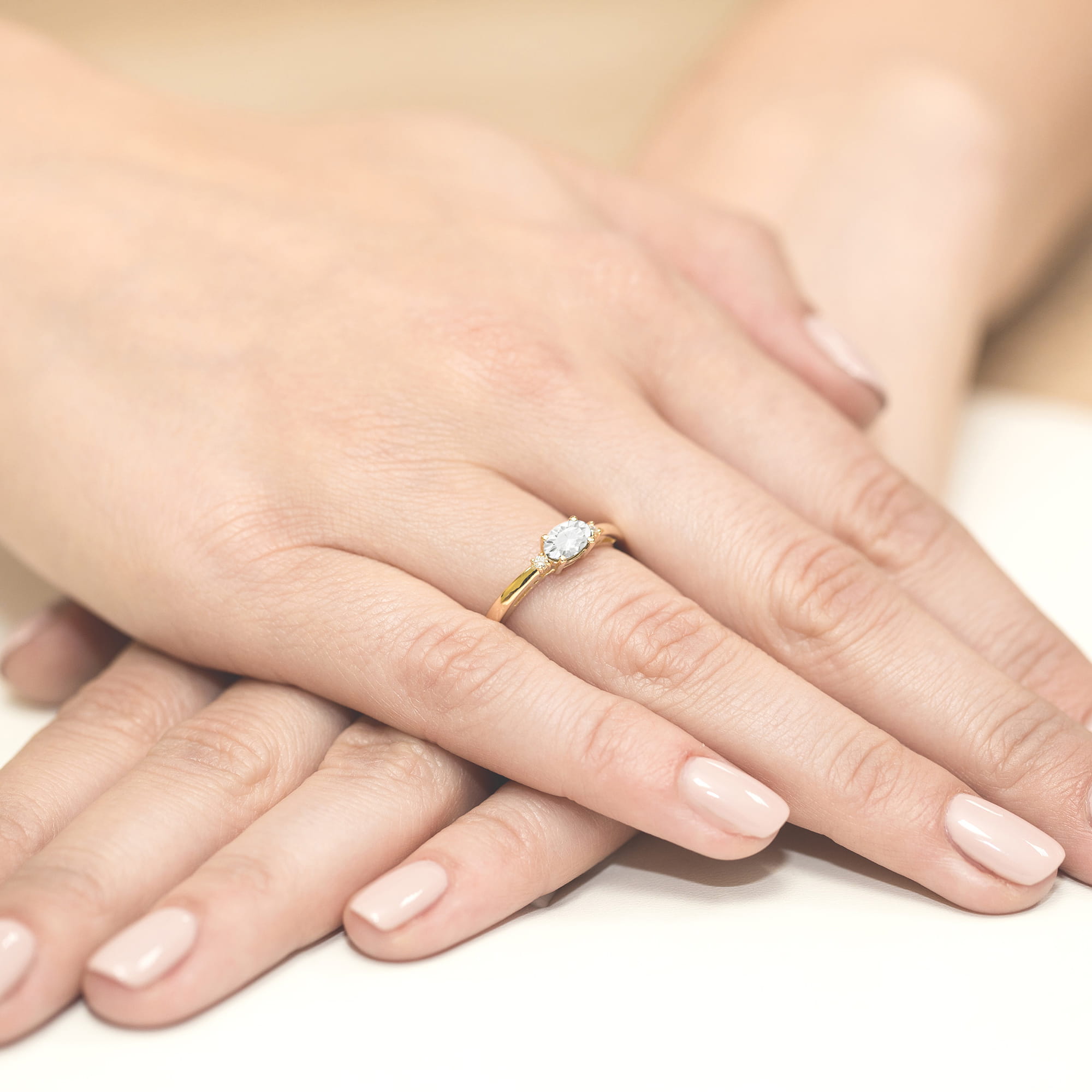 W0006.Z3.LDW.01_4 Złoty pierścionek z diamentem na palcu, dłonie z delikatnym manicure w jasnym kolorze.