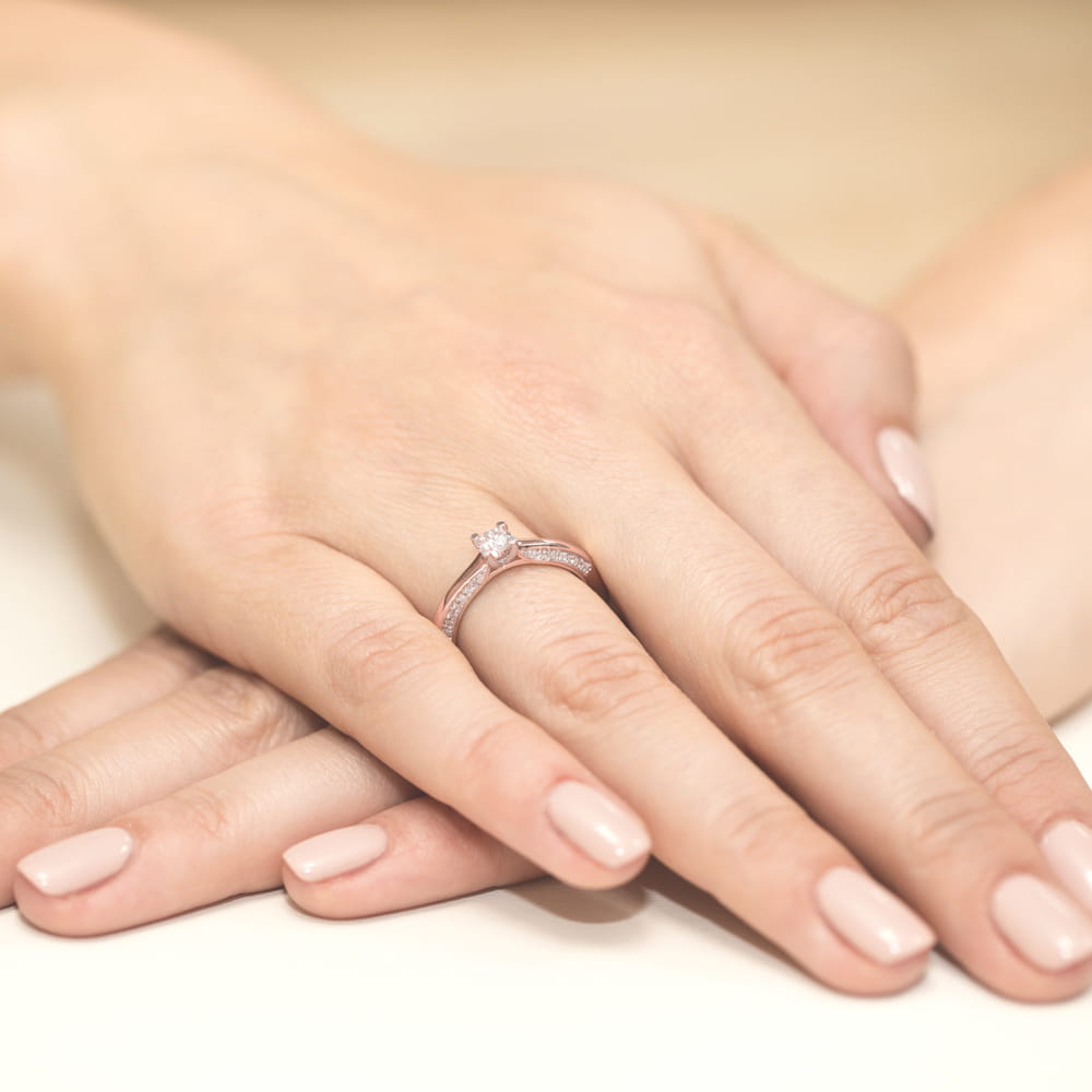 W0009.R3.DIW.01_5 Dwie dłonie z delikatnym pierścionkiem zaręczynowym na jednym z palców, paznokcie w jasnym kolorze.