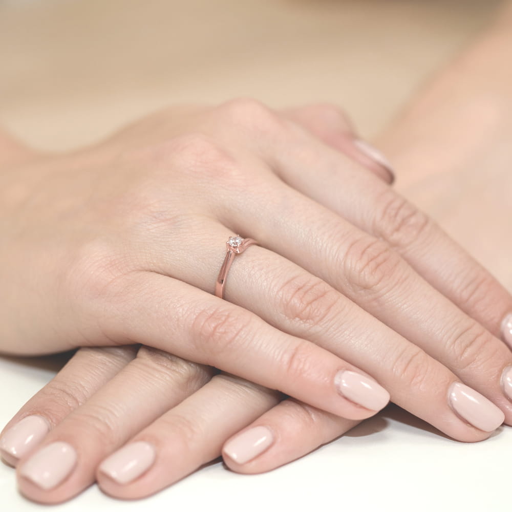 W0021.R3.DIW.01_4 Dwie dłonie z delikatnym pierścionkiem na palcu, z zadbanymi paznokciami w jasnym kolorze.