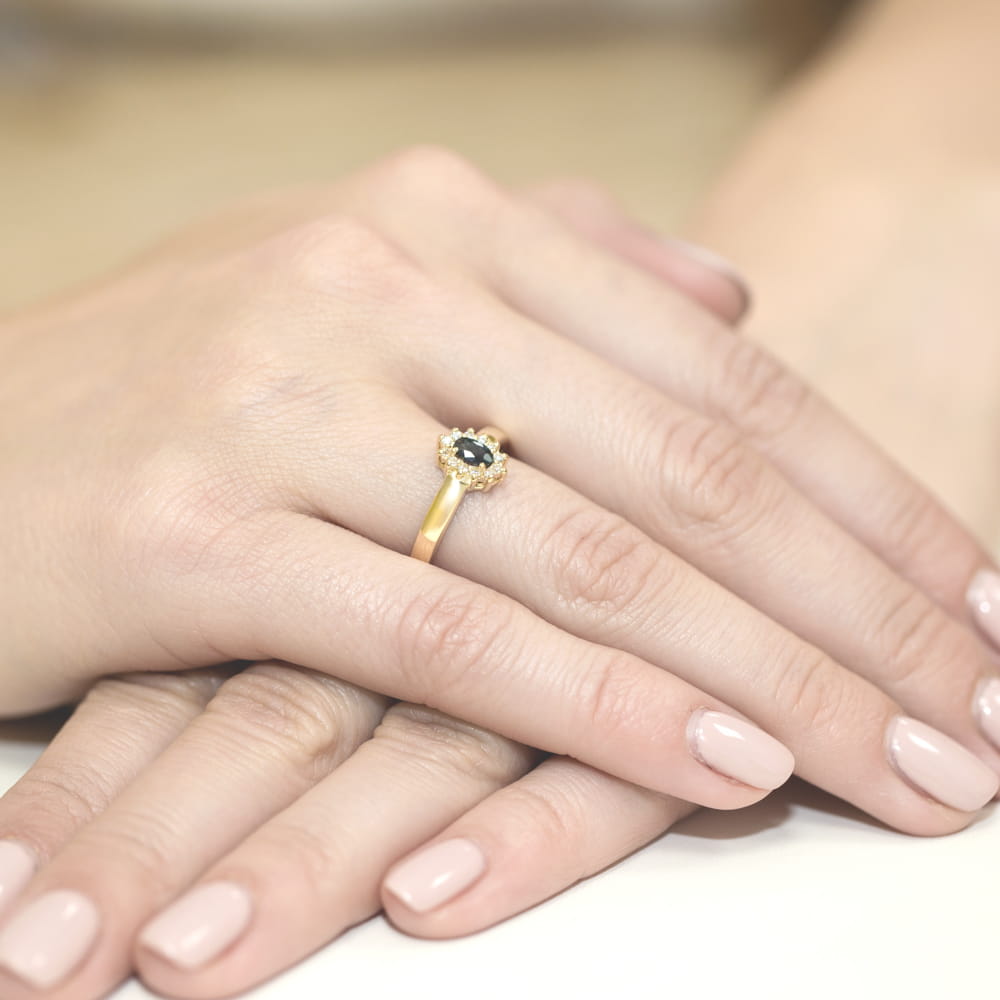 W0026.Z3.SAB.01_4 Złoty pierścionek z czarnym kamieniem na palcu, dłonie z zadbanymi paznokciami.