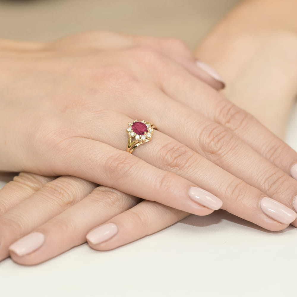 W0037.Z3.RUR.01_4 Złoty pierścionek z rubinem i diamentami na palcu, dłonie z delikatnym manicure w jasnym kolorze.