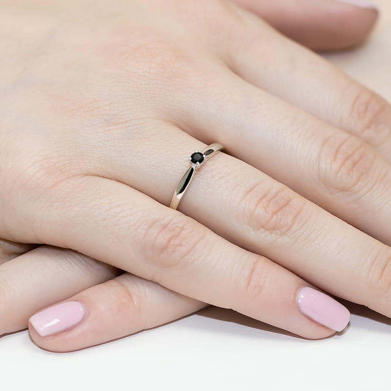 W0045.B3.DIB.01_4 Złoty pierścionek z czarnym kamieniem na palcu z różowym manicure.