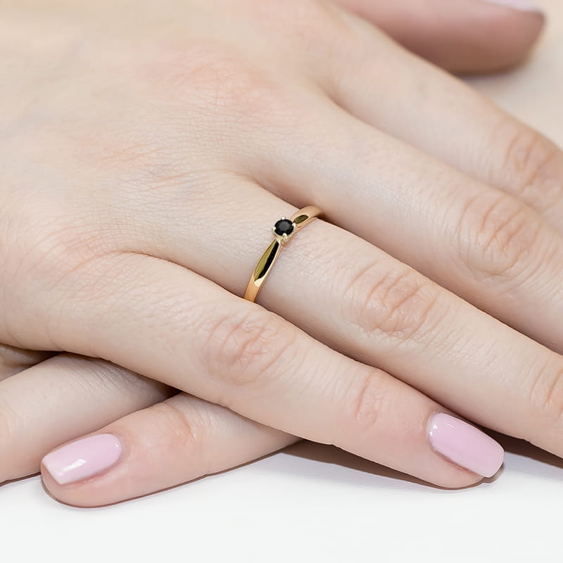W0045.Z3.DIB.01_4 Złoty pierścionek z czarnym kamieniem na palcu z różowym manicure.