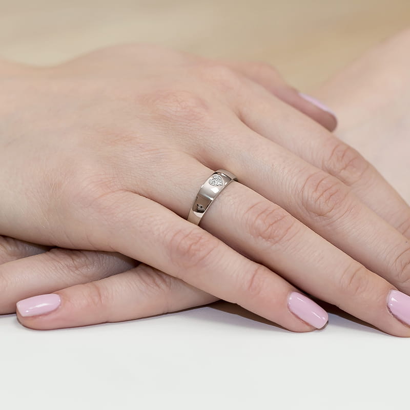 W0064.B3.DIW.01_4 Dwie ręce z delikatnym manicurem, jedna z nich nosi srebrny pierścionek z małym diamentem.