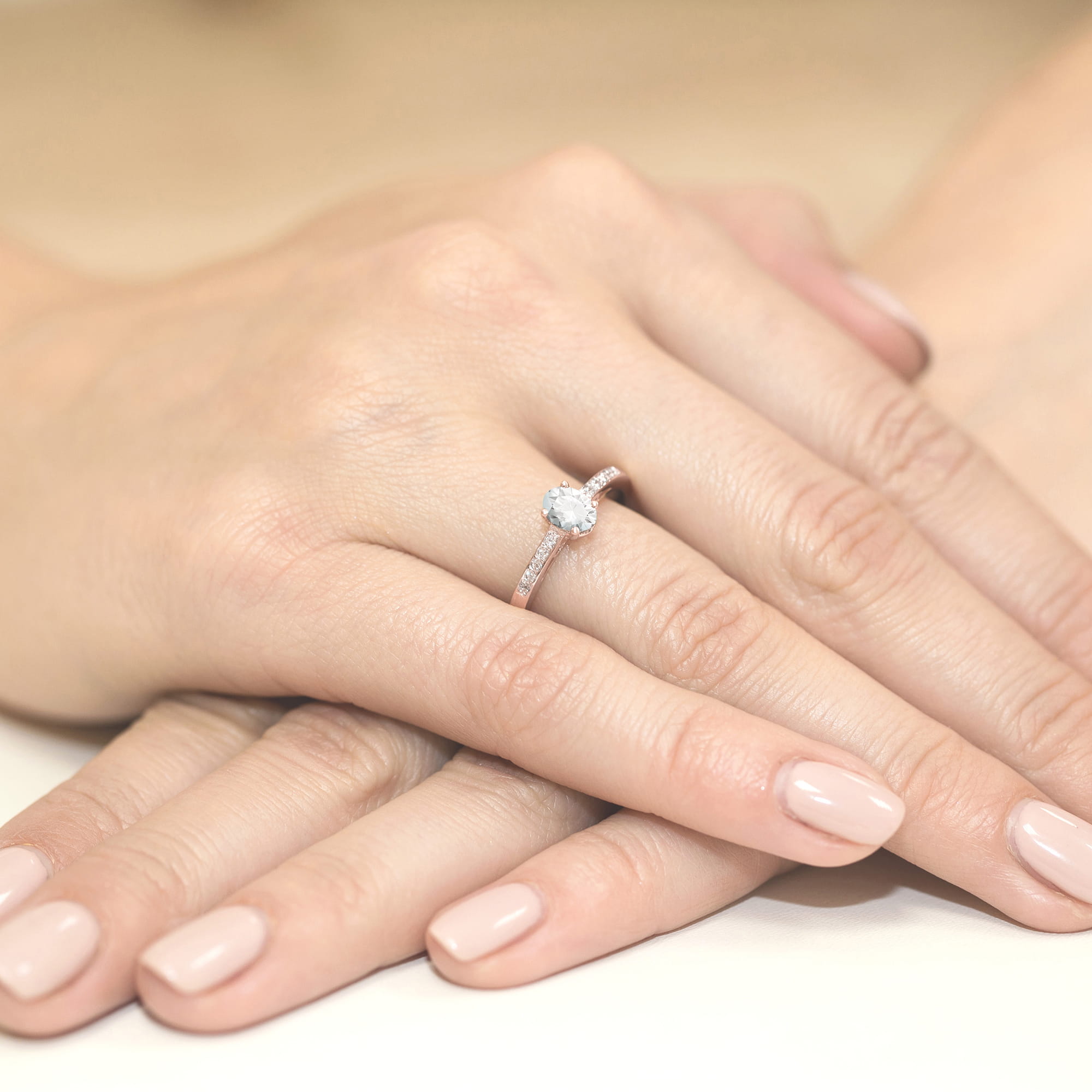 W0067.R3.LDW.01_3 Na dłoni z delikatnym manicure znajduje się pierścionek z dużym, okrągłym diamentem.