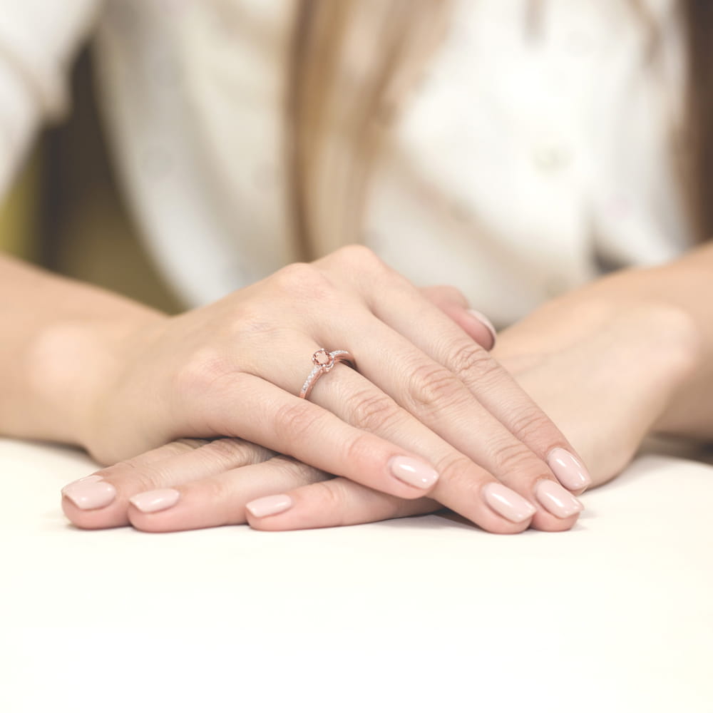 W0067.R3.MOP.01_3 Dwie dłonie z delikatnym pierścionkiem na palcu, z zadbanymi paznokciami w jasnym kolorze.