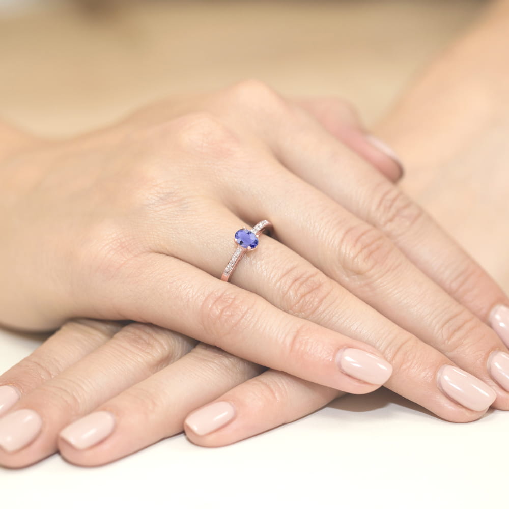 W0067.R3.TAP.01_3 Pierścionek z niebieskim kamieniem na palcu, dłonie z zadbanymi paznokciami w jasnym kolorze.