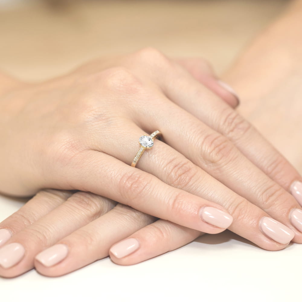 W0067.Z3.SAW.01_3 Zbliżenie na rękę z delikatnym pierścionkiem zaręczynowym na palcu, z gładkimi paznokciami.