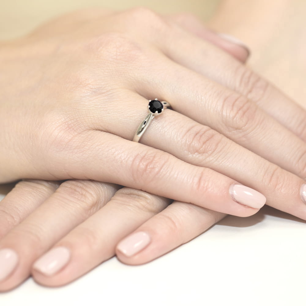 W0074.B3.DIB.02_4 Dwie dłonie z delikatnym manicure, na jednej z nich srebrny pierścionek z czarnym kamieniem.