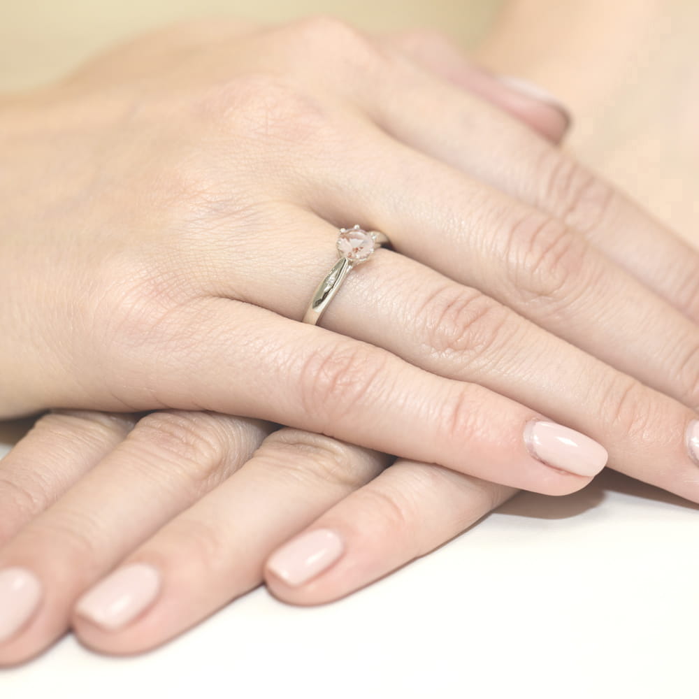 W0074.B3.MOP.01_4 Dwie ręce z delikatnym manicure, jedna z pierścionkiem z różowym kamieniem na palcu.
