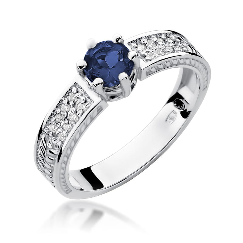 W0075.B3.SAB.01_1 Srebrny pierścionek z niebieskim kamieniem szlachetnym i ozdobnymi diamentami po bokach.