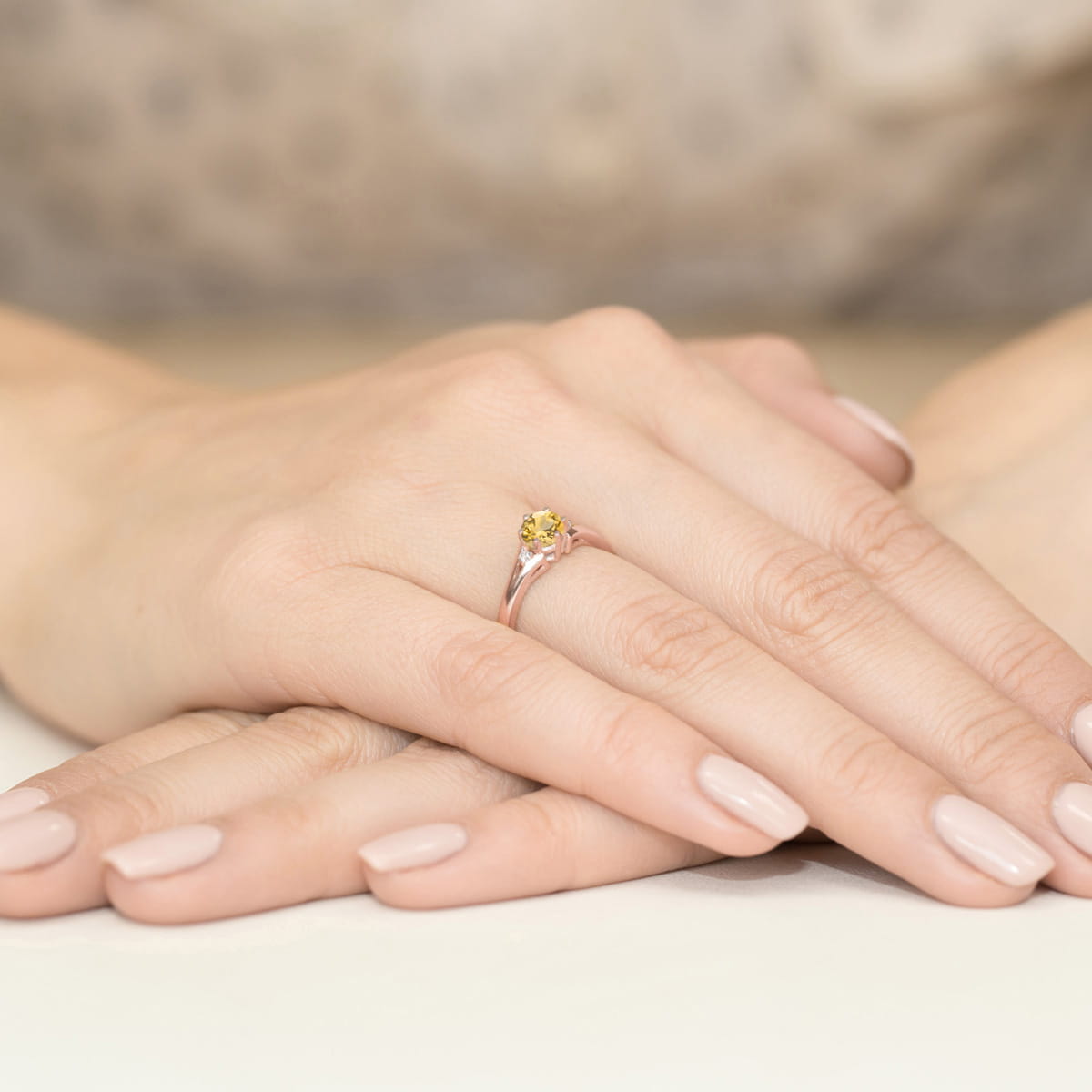 W0076.R3.CIY.01_4 Złoty pierścionek z żółtym kamieniem na palcu, dłonie z delikatnym manicure w jasnym kolorze.