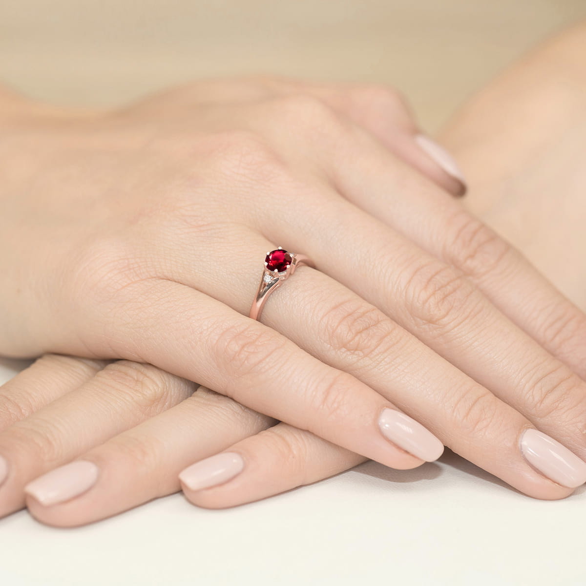 W0076.R3.RUR.01_4 Różowa pierścionek z czerwonym kamieniem na dłoniach z delikatnym manicure.