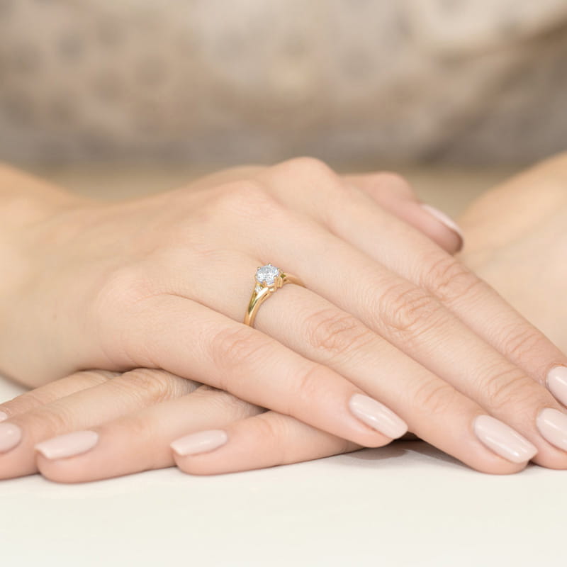 W0076.Z3.LDW.01_4 Złoty pierścionek z diamentem na palcu, dłonie z delikatnym manicure w neutralnym kolorze.