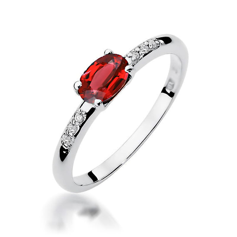 W0077.B3.RUR.01_1 Srebrny pierścionek z owalnym, czerwonym kamieniem i ozdobnymi diamentami po bokach.
