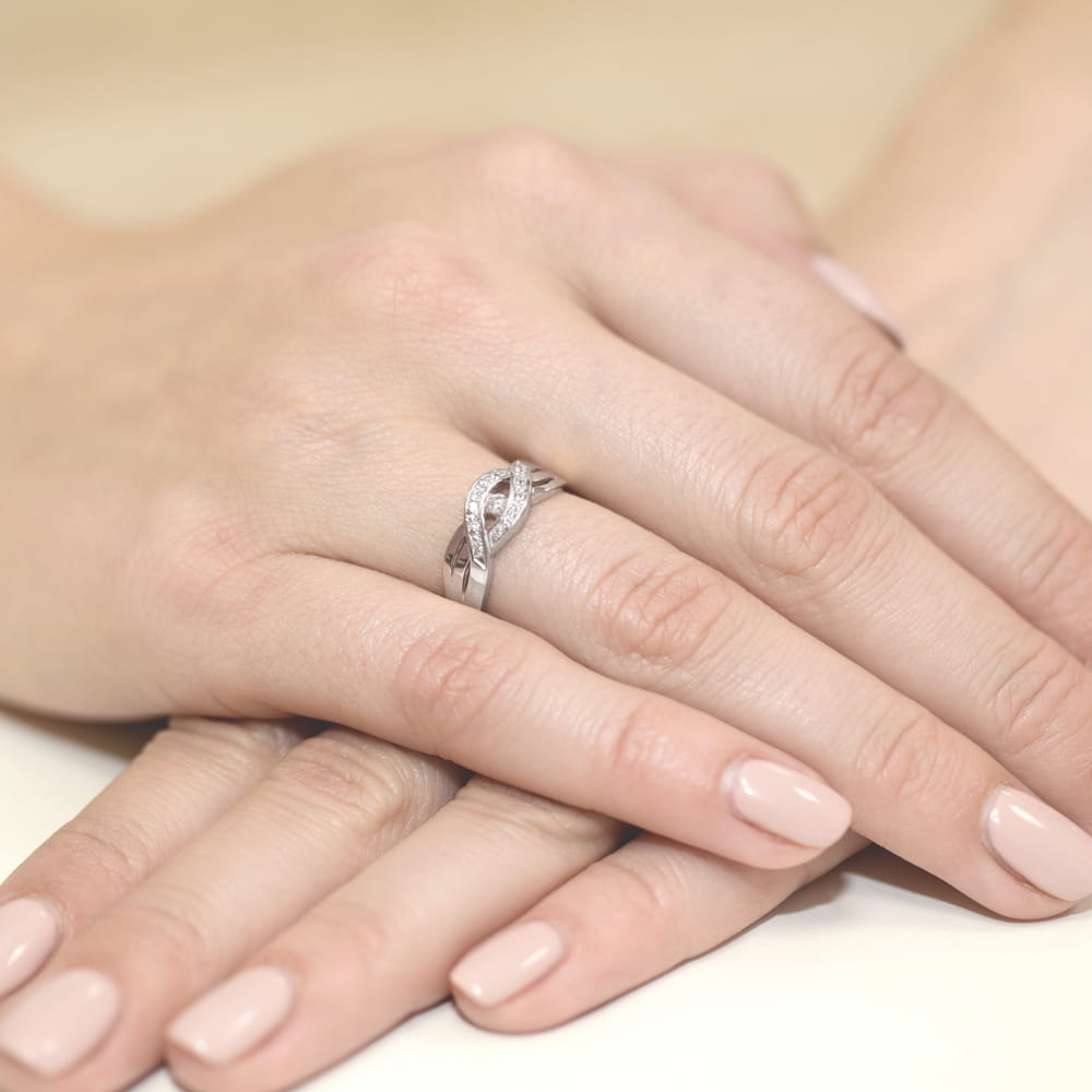 W0083.B3.DIW.01_4 Srebrny pierścionek z diamentami na palcu, dłonie z delikatnym manicure w jasnym kolorze.
