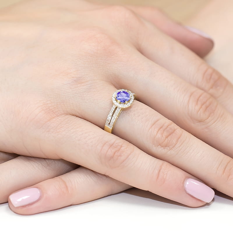 W0087.Z3.TAP.01_4 Złoty pierścionek z fioletowym kamieniem otoczonym diamentami na dłoni z różowym manicure.