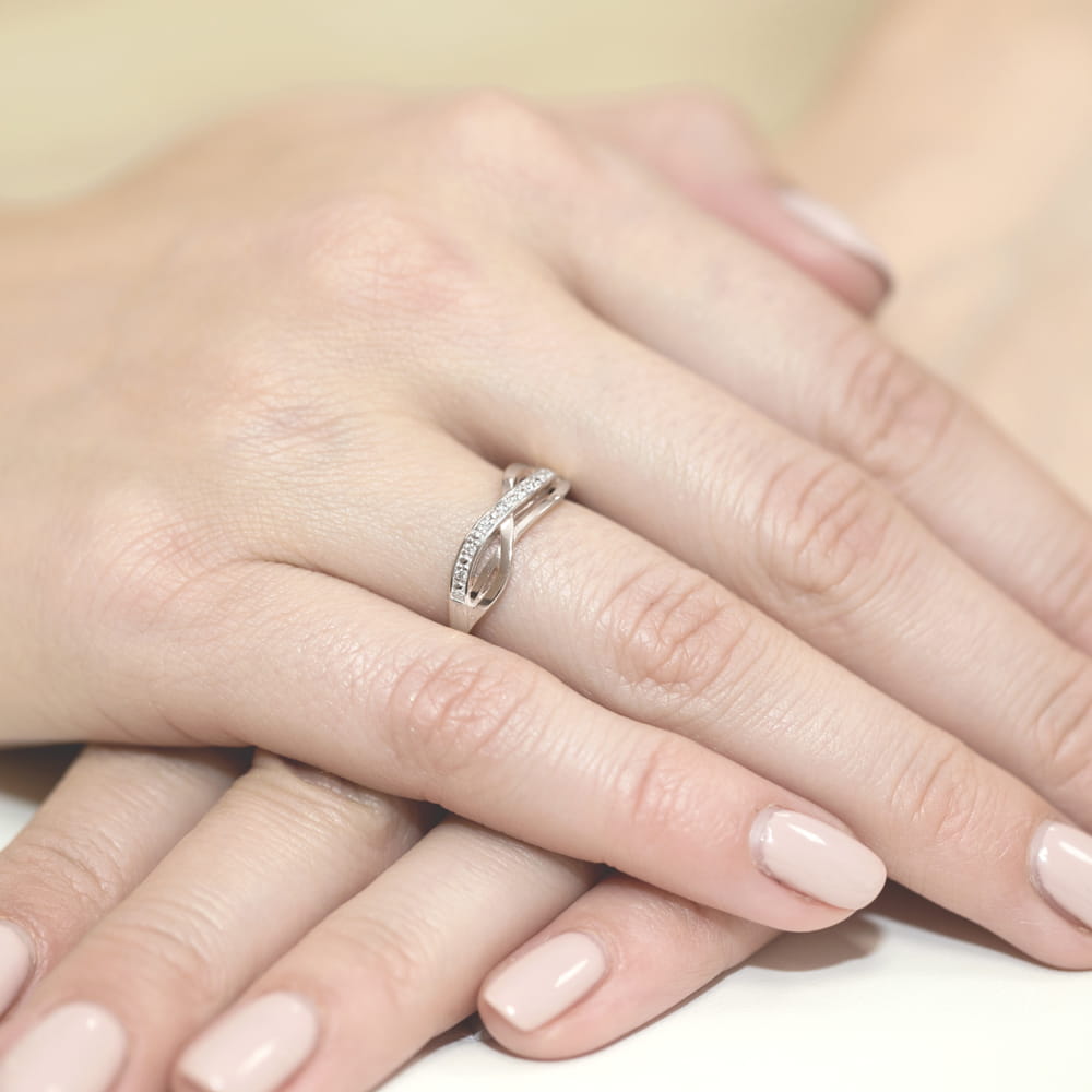 W0090.B3.DIW.01_4 Na dłoni widoczny srebrny pierścionek z diamentami, otoczony delikatnymi, zadbanymi paznokciami.
