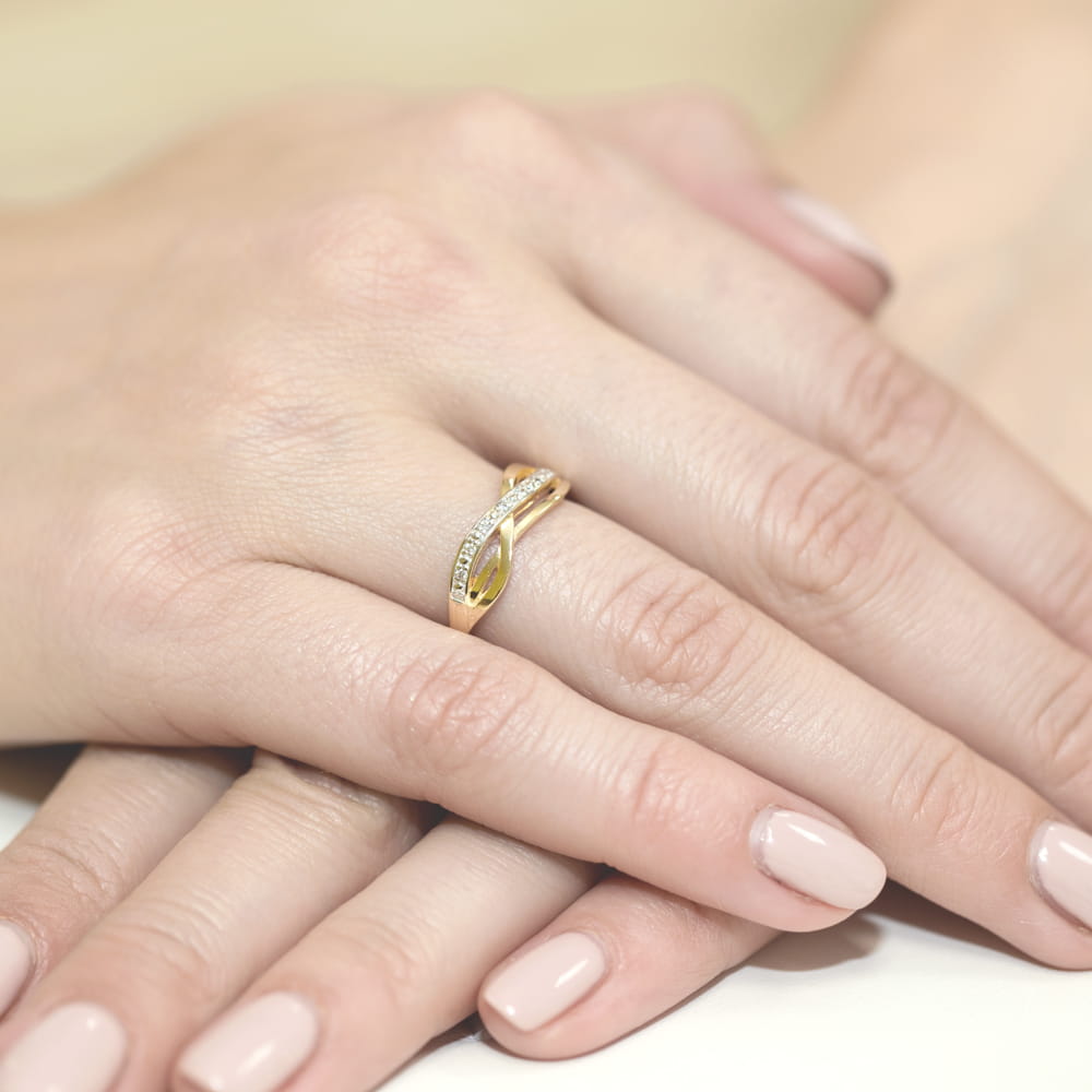 W0090.Z3.DIW.01_4 Złoty pierścionek z diamentami na palcu kobiecej ręki, delikatne paznokcie w jasnym kolorze.