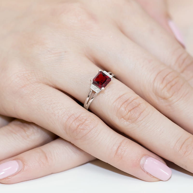 W0103.B3.GAR.01_4 Pierścionek z czerwonym kamieniem szlachetnym na palcu z delikatnymi zdobieniami.