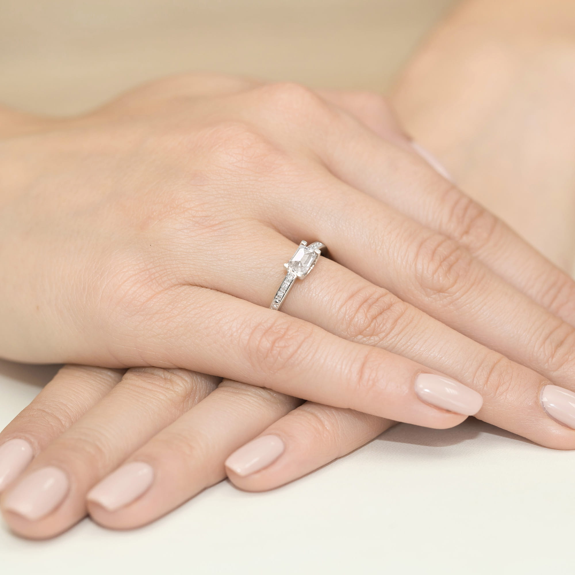 W0105.B3.LDW.01_4 Srebrny pierścionek z diamentem w kształcie prostokąta na palcu z delikatnymi, zadbanymi paznokciami.