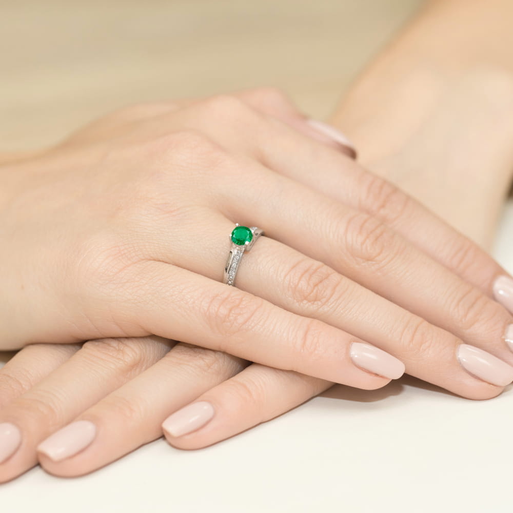 W0106.B3.EMG.01_4 Dwie dłonie z delikatnym manicurem, na jednej z nich pierścionek z zielonym kamieniem szlachetnym.