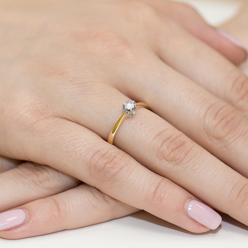 W0111.Z3.DIW.05_4 Złoty pierścionek z diamentem na palcu, dłonie z delikatnym manicure w jasnym kolorze.