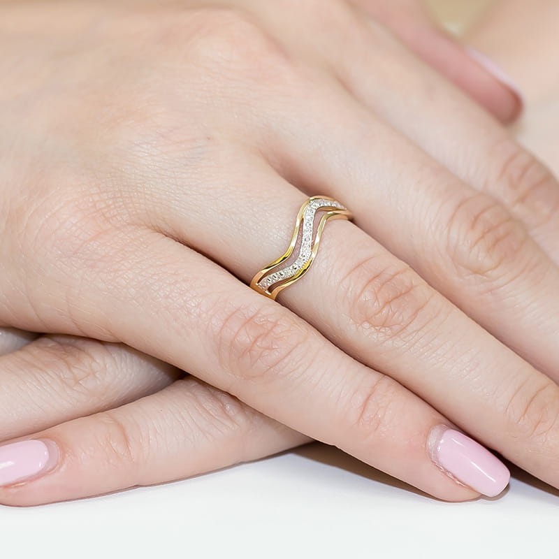 W0116.Z3.DIW.01_4 Złoty pierścionek w falistym kształcie z diamentami na palcu z różowym manicure.