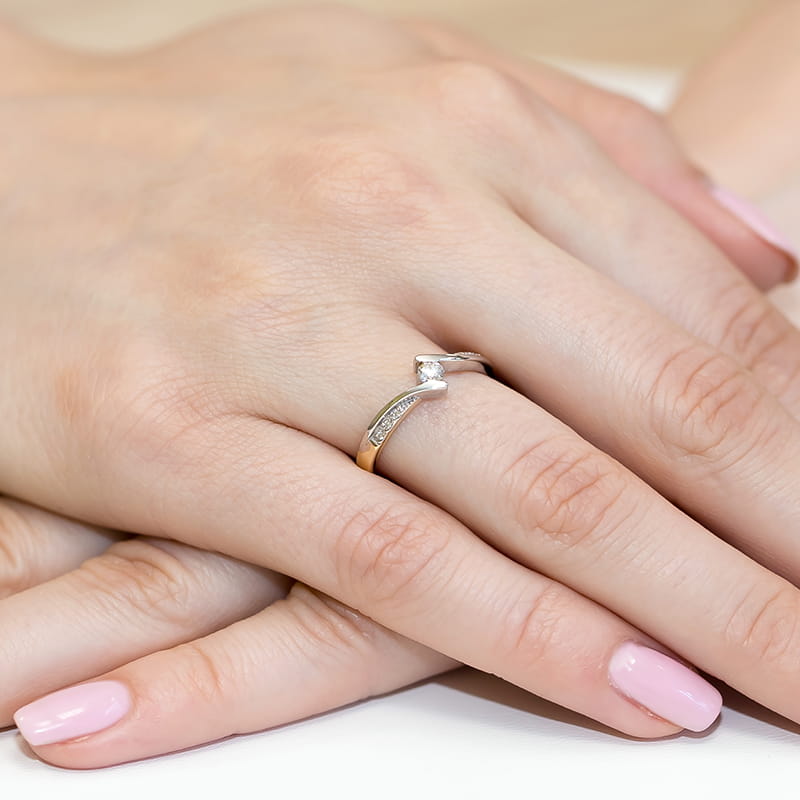 W0177.Z3.DIW.01_4 Na dłoni z różowym manicure widoczny jest srebrny pierścionek z diamentami.