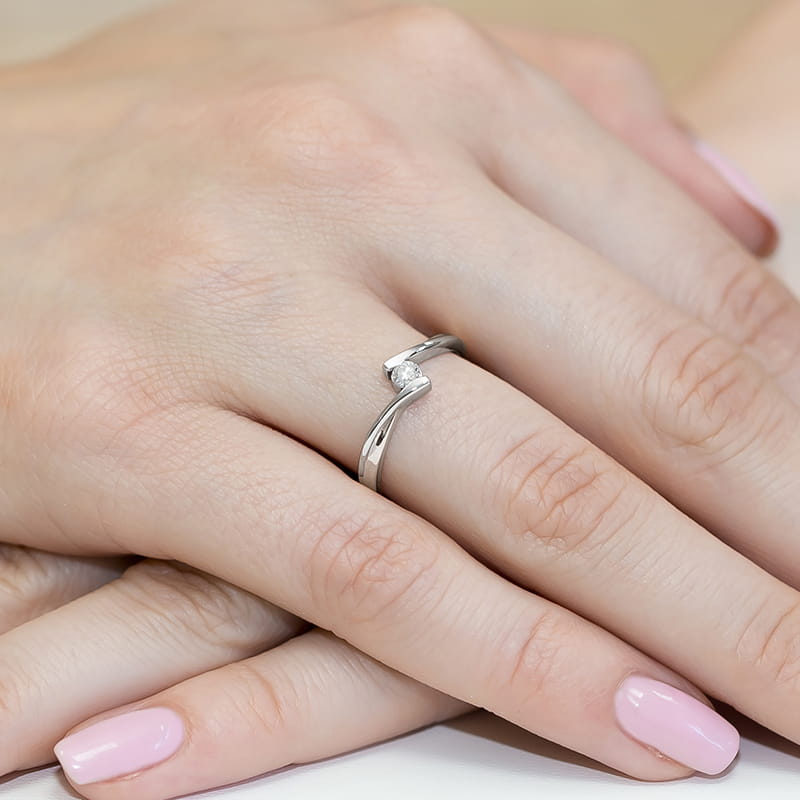 W0180.B3.DIW.01_4 Srebrny pierścionek z małym diamentem na dłoni z różowym manicure.