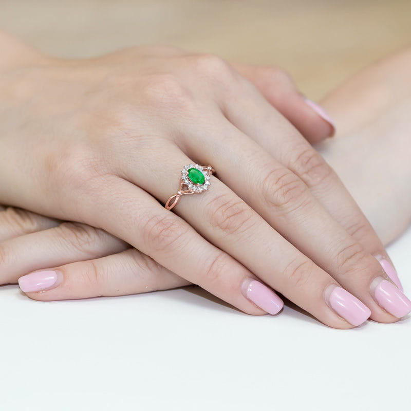 W0182.R3.EMG.01_4 Różowa pierścionek z zielonym kamieniem w otoczeniu małych, jasnych kryształków na dłoni z różowym manicure.