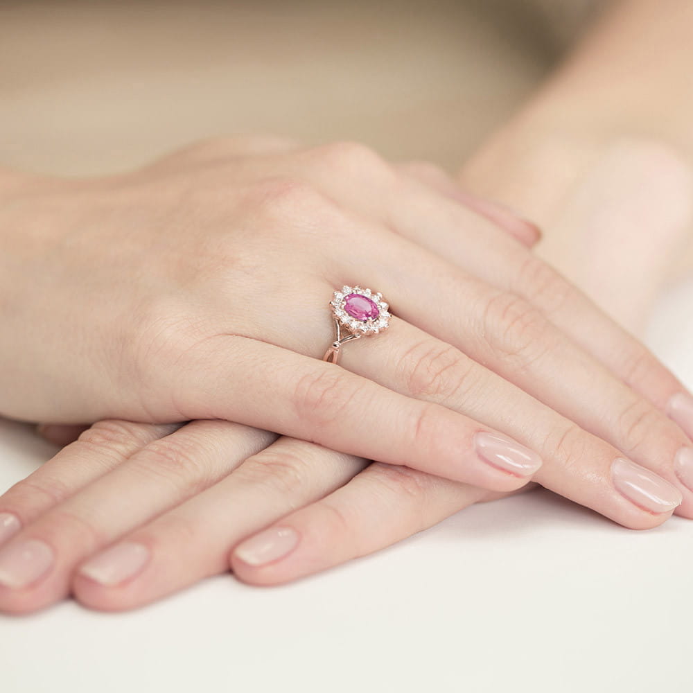 W0182.R3.TOP.01_4 Różowa pierścionek z diamentami na dłoni, otoczony delikatnymi, jasnymi paznokciami.