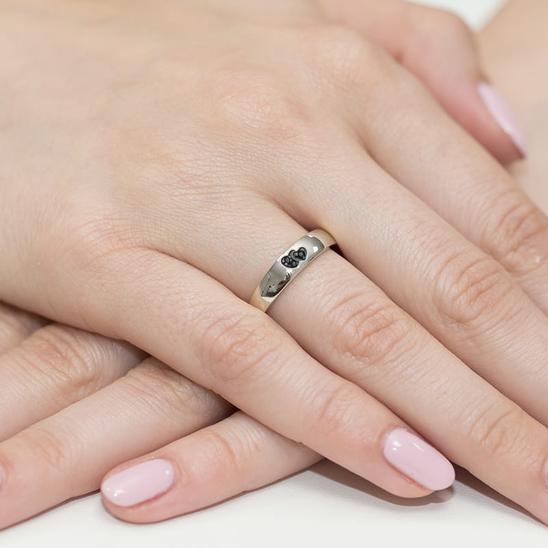 W0189.B3.DIB.01_6 Na dłoni widoczny srebrny pierścionek z czarnymi kamieniami, otoczony delikatnymi, różowymi paznokciami.