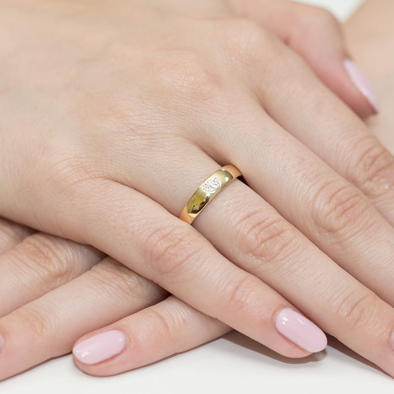 W0189.Z3.DIW.01_4 Złoty pierścionek na palcu kobiecej ręki z delikatnym manicure w jasnym kolorze.