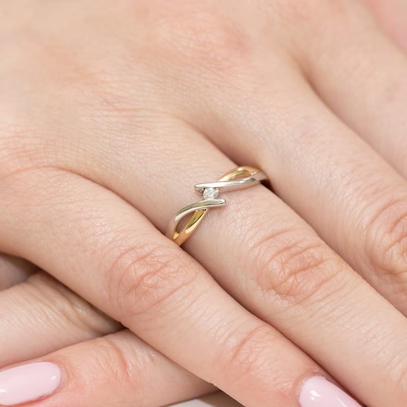 W0191.Z3.DIW.01_4 Złoty pierścionek z diamentem, delikatnie skręcony, na palcu kobiety.