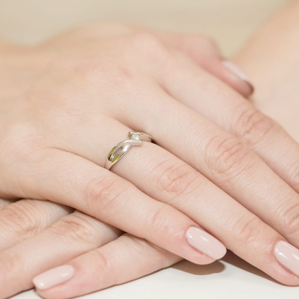 W0191.Z3.DIW.03_4 Srebrny pierścionek z małym diamentem na palcu kobiecej ręki, z delikatnym manicure.