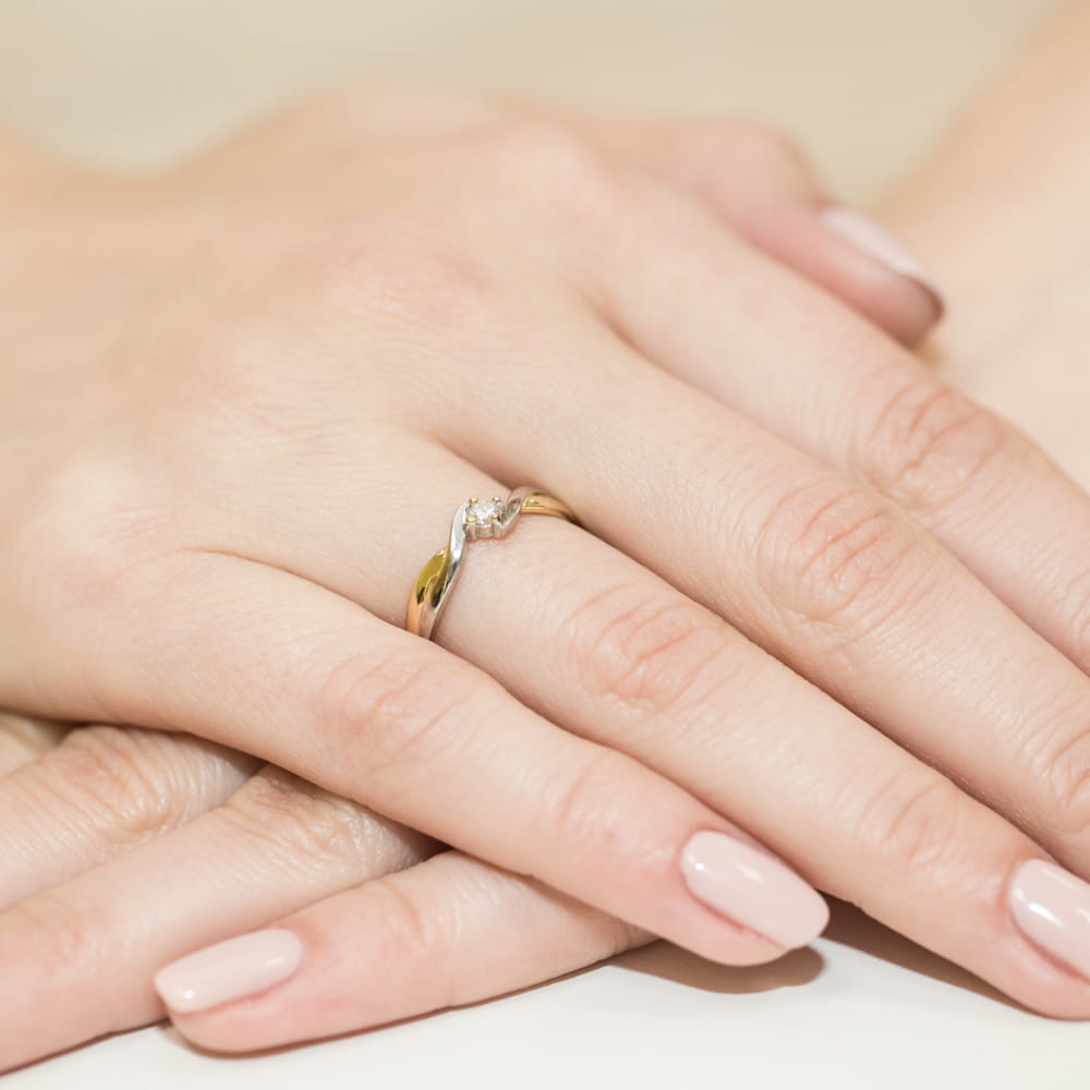 W0208.Z3.DIW.02_4 Złoty pierścionek z diamentem na palcu, dłonie z delikatnym manicure w jasnym kolorze.