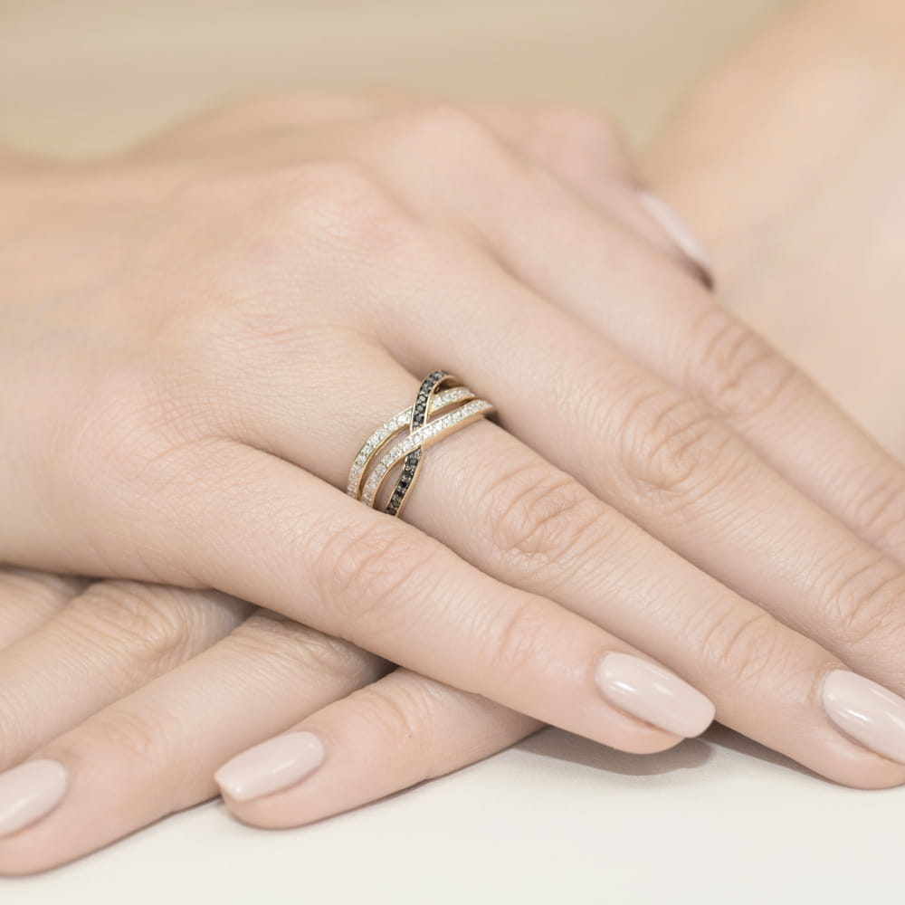 W0215.Z3.DIB.01_4 Na dłoni widoczny pierścionek z diamentami w złotej oprawie, otoczony delikatnymi, zadbanymi paznokciami.