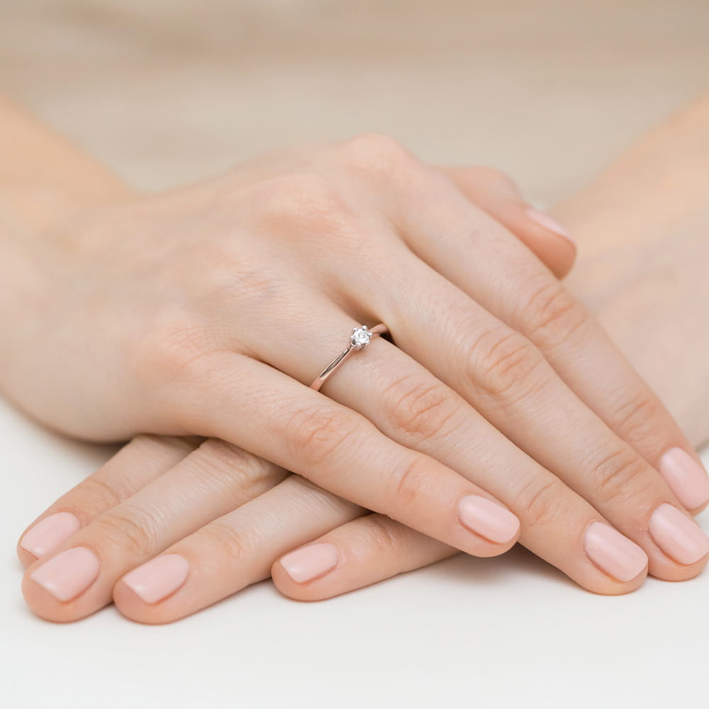 W0222.R3.DIW.12_10 Dwie dłonie z delikatnym pierścionkiem na palcu, z zadbanymi paznokciami w jasnym kolorze.