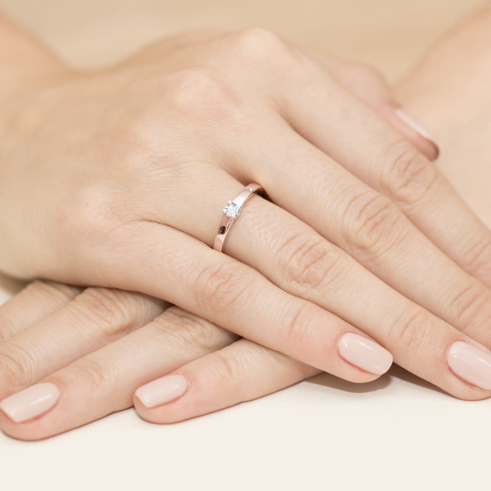 W0225.R3.DIW.03_4 Na dłoniach z delikatnym manicure znajduje się złoty pierścionek z małym diamentem.