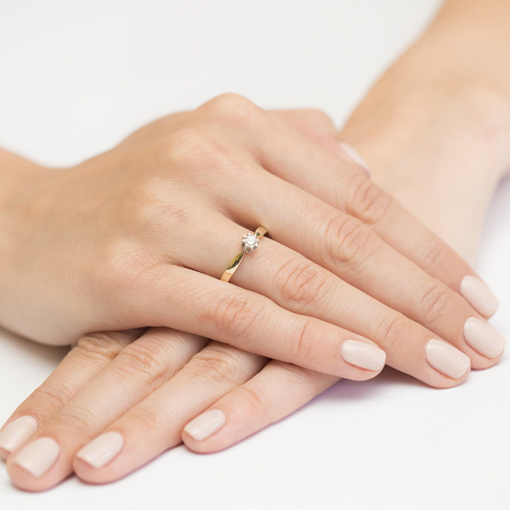 W0228.Z3.LDW.03_4 Dwie dłonie z delikatnym pierścionkiem zaręczynowym na palcu, z jasnym manicure.