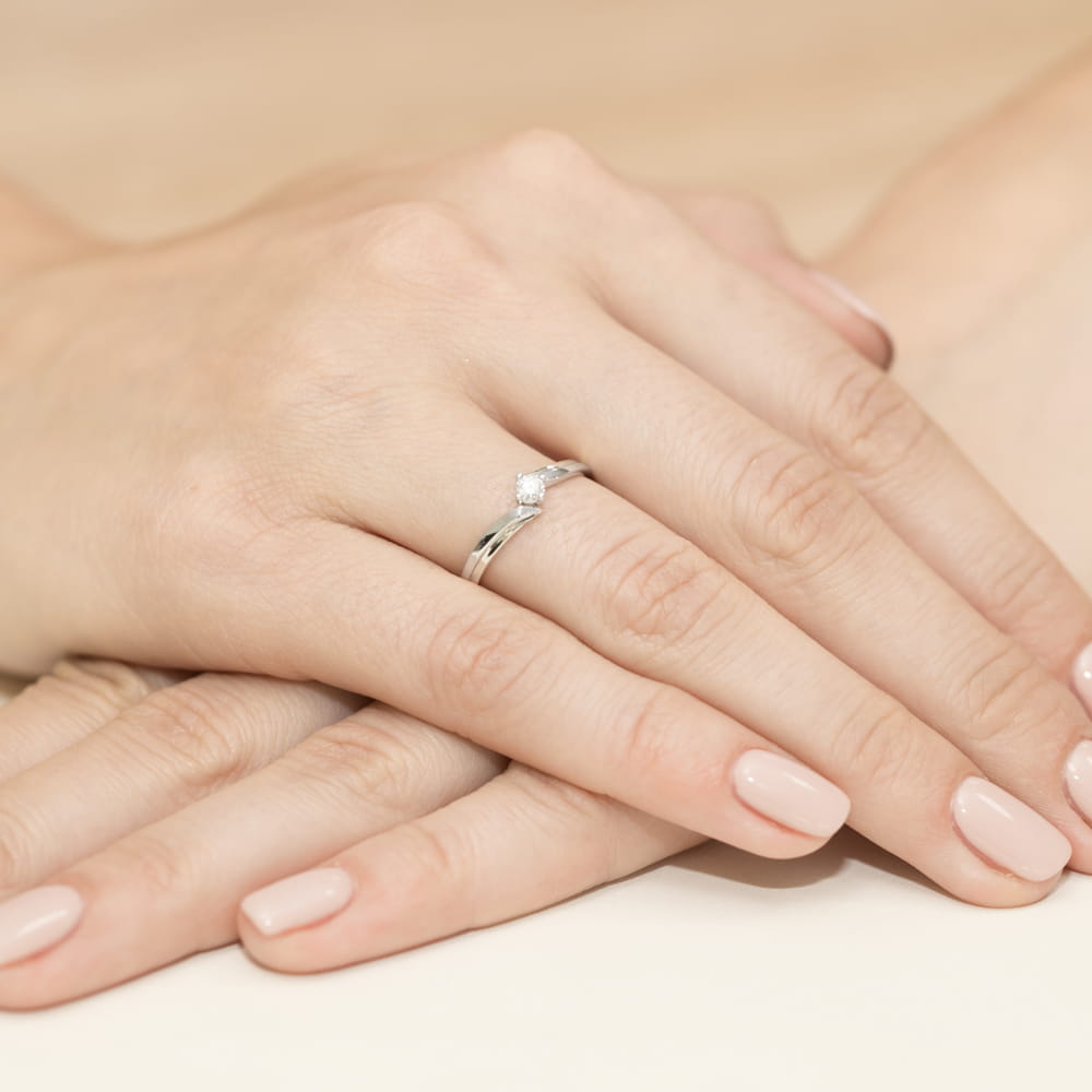 W0231.B3.LDW.05_4 Dwie dłonie z delikatnym pierścionkiem zaręczynowym na jednym z palców, z gładkimi paznokciami.